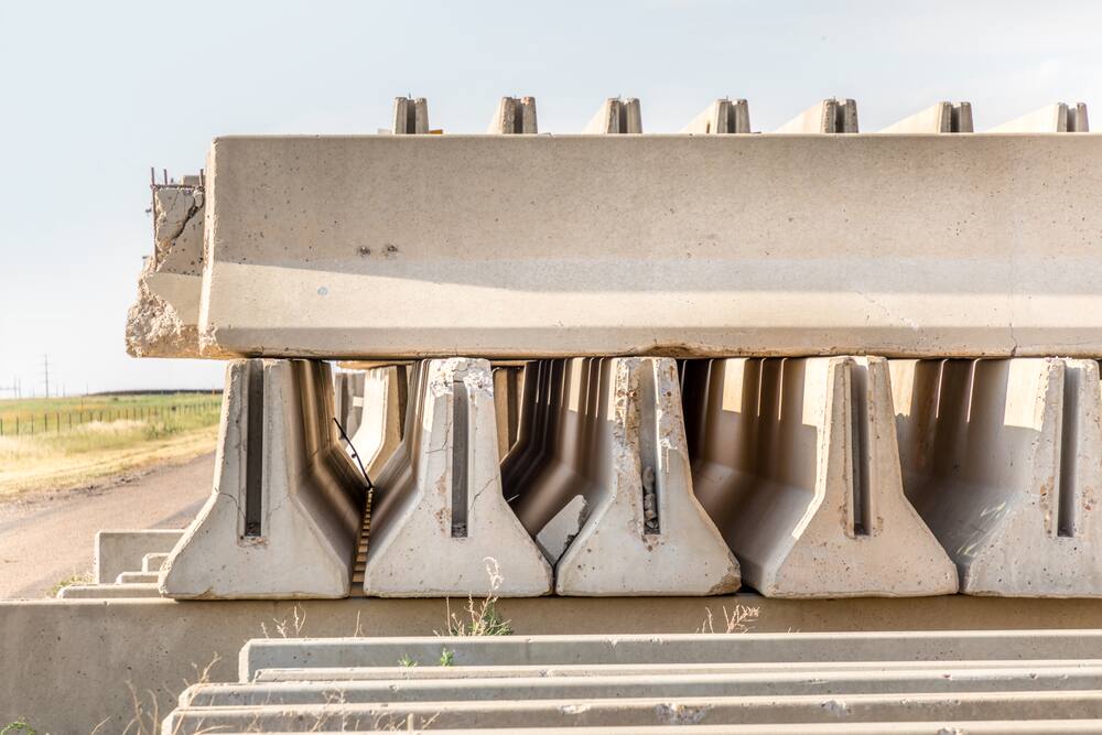Precast concrete barriers stacked beside a rural road before installation